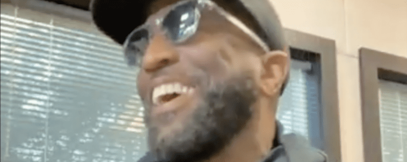 Man smiling, wearing sunglasses and hat.